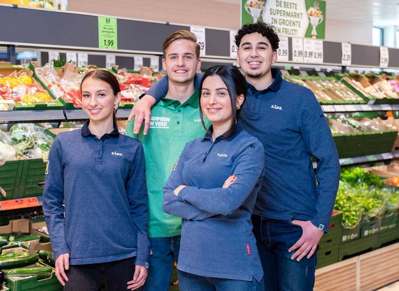 Groep Lidl supermarkt collega's staan bij de groente en fruit