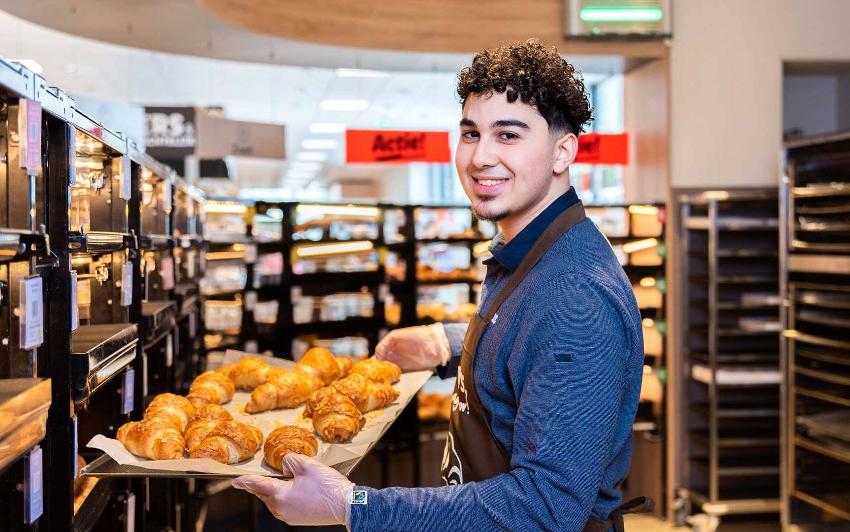 Verkoopmedewerker in de bakkerij met een tree croissants