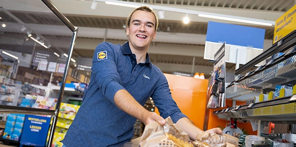Verkoopmedewerker bij de kassaband met brood
